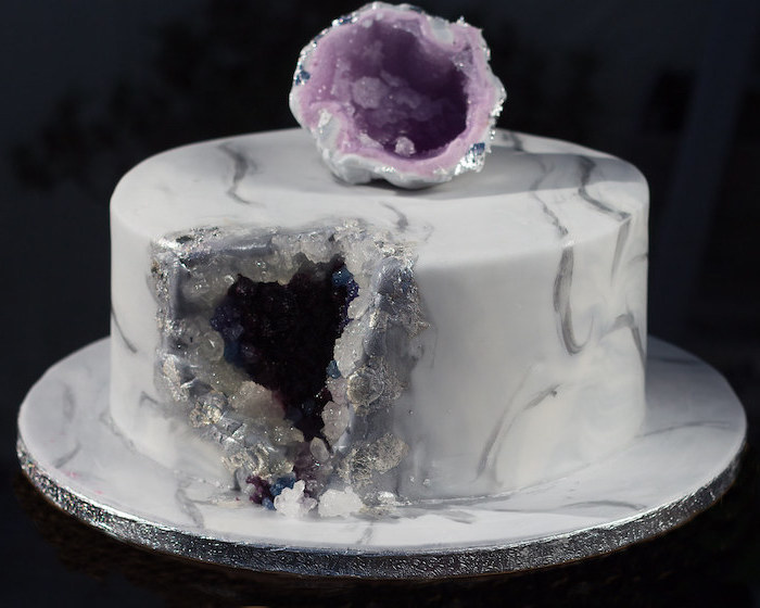 one tier cake, covered with white and grey marble fondant, geode birthday cake, decorated with black and purple rock candy