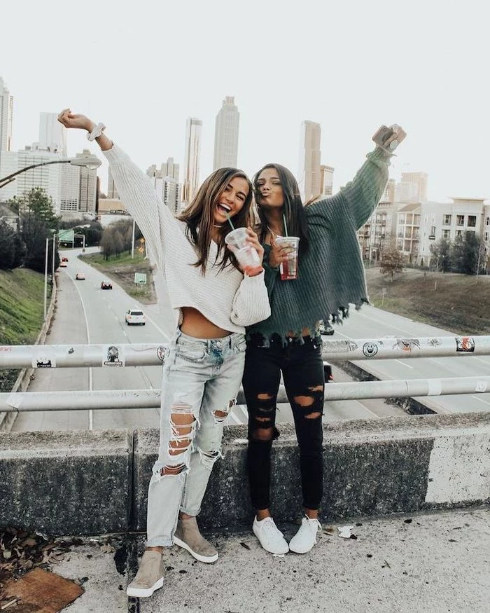 two girls standing on a bridge over a highway, middle school outfits, wearing ripped jeans and knitted sweaters