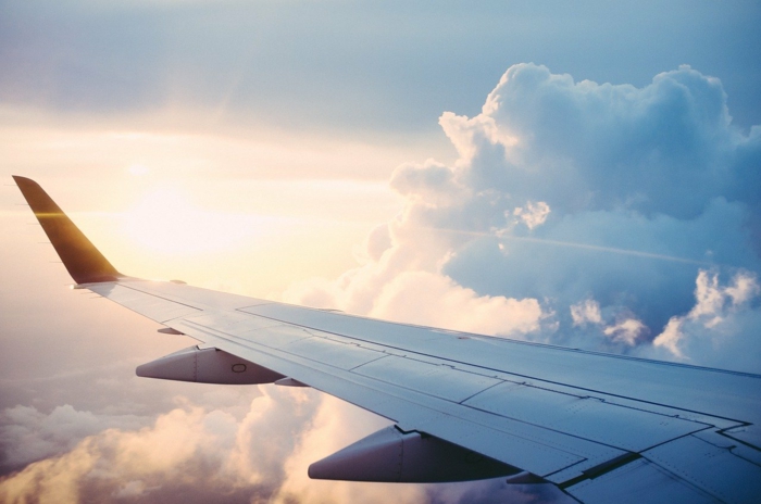 wing of a plane, flying above the clouds, photographed from inside the plane, cheapest flights, sun shining