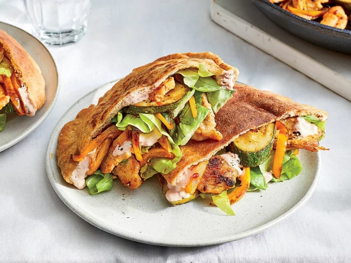 pita bread with chicken and vegetables inside, easy dinners for two, placed on white plate on white surface