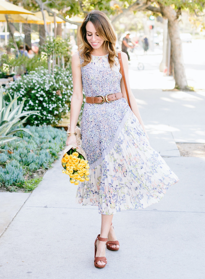 woman walking down the sidewalk, wearing a white dress with floral print, pretty dresses for women, holding a bouquet of yellow flowers