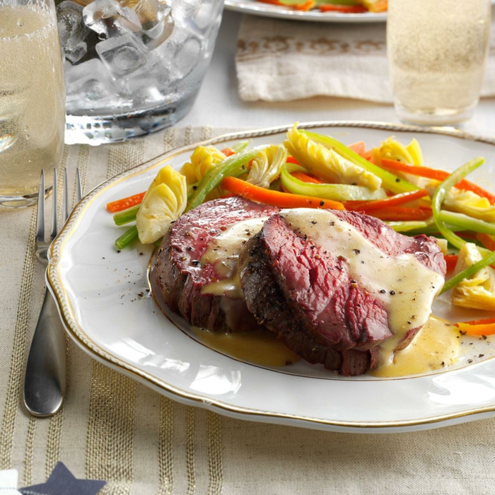 baked meat covered with creame sauce, stemed vegetables on the side of white plate, easter dinner ideas no ham