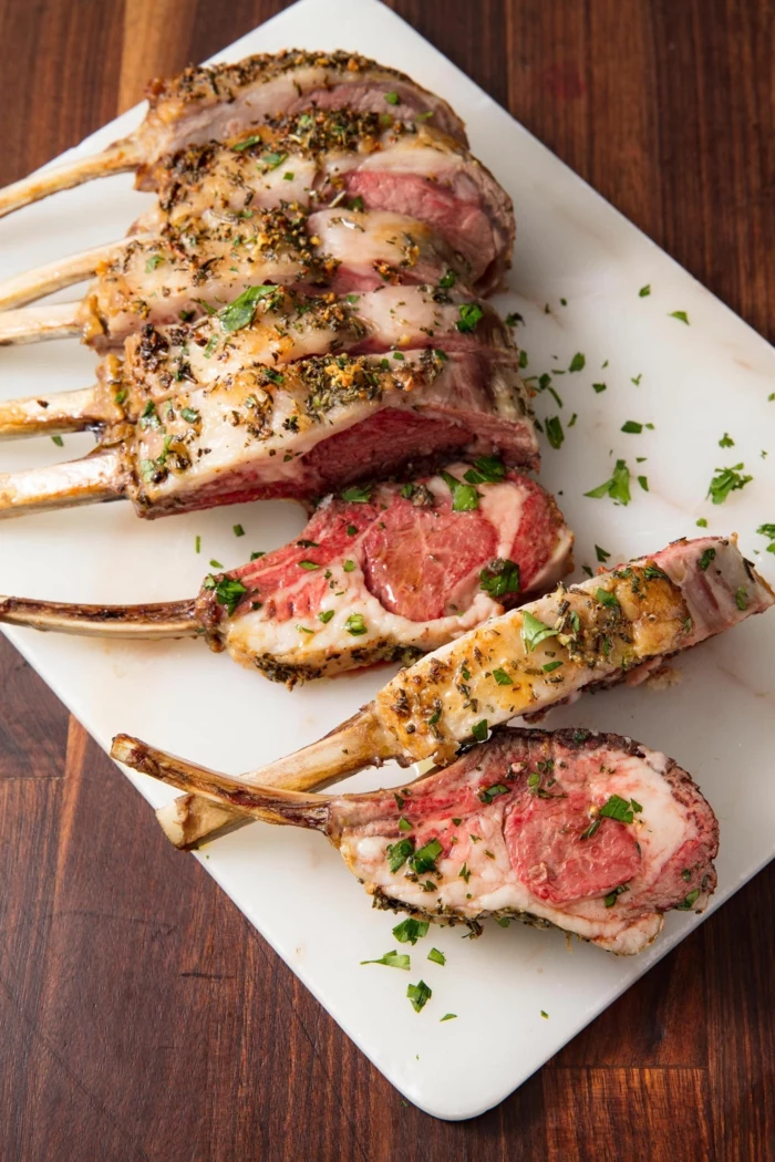 rack of lamb with creamy sauce, garnished with chopped parsley, easter buffet 2019, white plate on wooden table