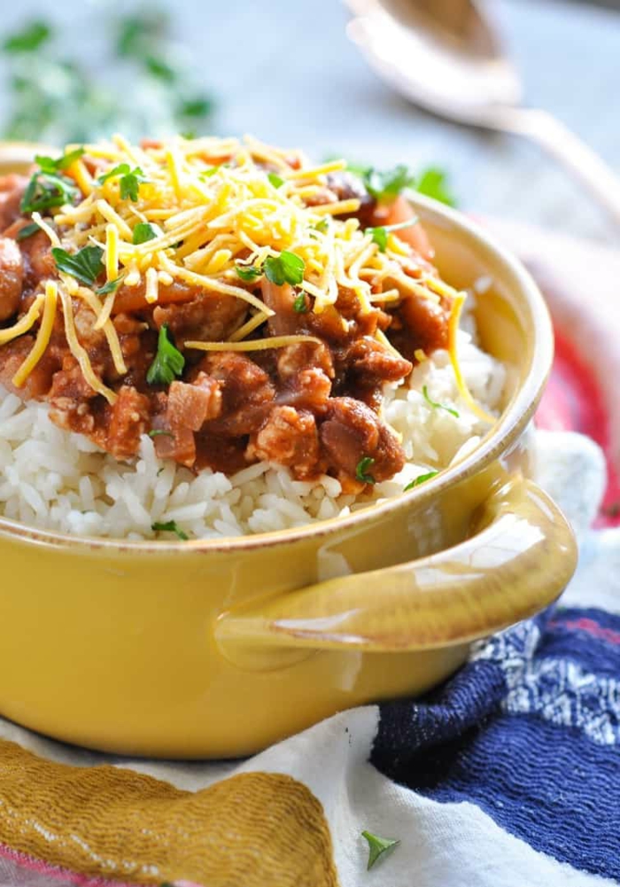 beans and meat rice, shredded cheese on top, garnished with parsley, easy dinner ideas for two, placed in yellow ceramic bowl