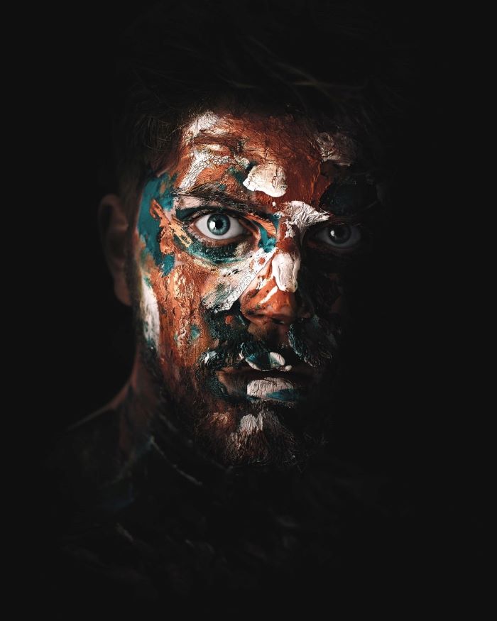 realistic painting of a man with blue eyes, covered in paint, black background, how to draw cute eyes