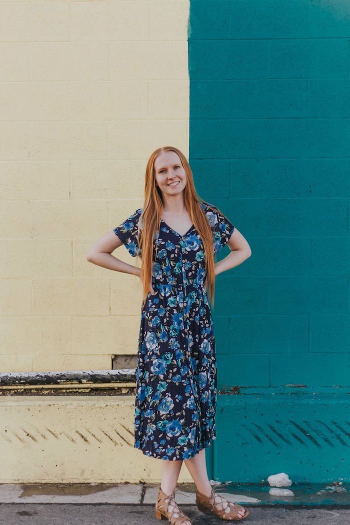 woman with long red hair, wearing a navy blue dress with floral print, brown flat sandals, pretty dresses for women