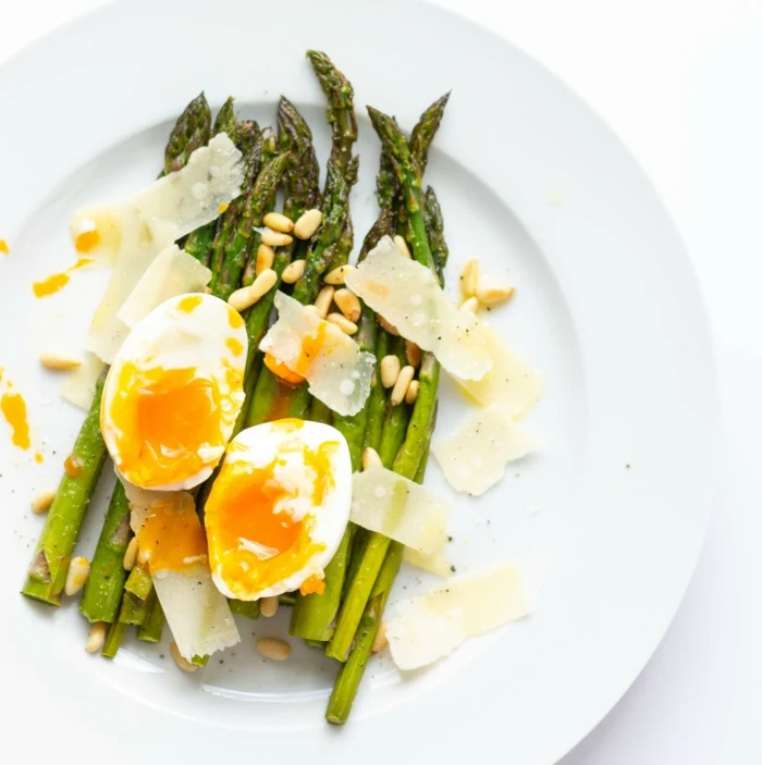 roasted asparagus with seeds, halved boiled egg and parmesan on top, placed on white plate, easter buffet 2019