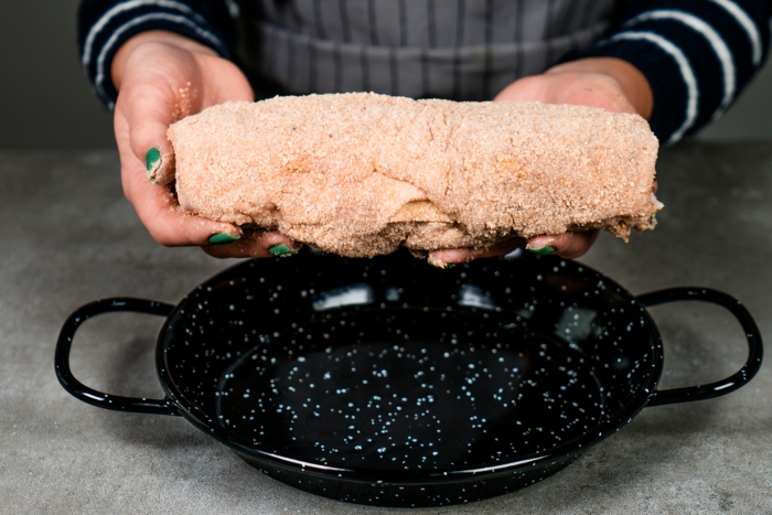 rolled up chicken breast, held by woman with green nail polish, chicken cordon bleu recipe, black pan
