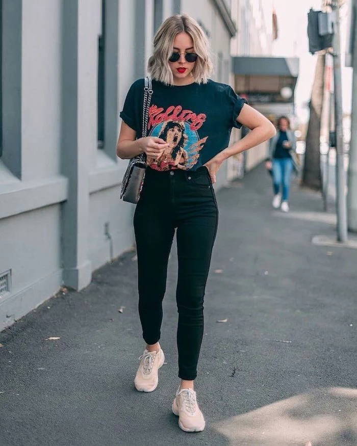 blonde woman walking on a sidewalk, wearing black jeans, black rolling stones t shirt, cute first day of school outfits, white sneakers