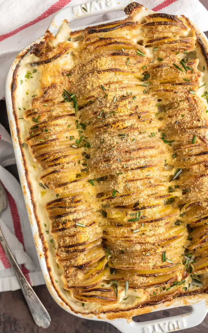 garlic and herb scalloped potatoes, sliced and arranged in a white casserole dish, rosemary on top, easter dinner ideas