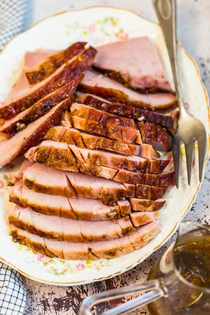 slices of ham arranged on white plate, fork on the side, easter meal ideas, baked ham with marmalade glaze