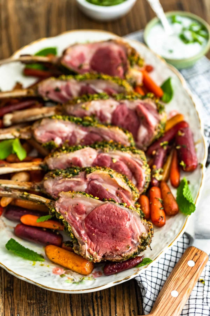 slices of rack of lamb, easter dishes, arranged on white plate, roasted baby carrots around it