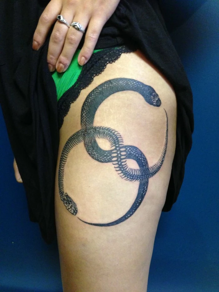 thigh tattoo, snake and snake skeleton intertwined, formin an infinity symbol, what does ouroboros mean