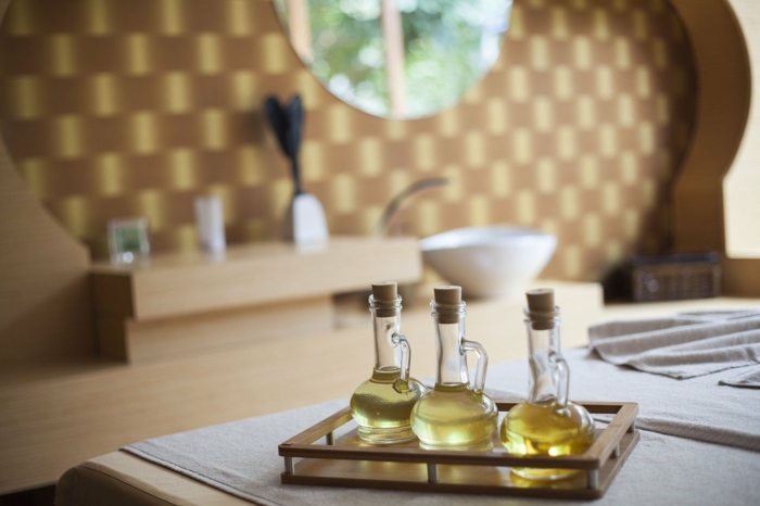 three glass bottles, filled with different oils, placed on a tray, spa holidays, placed on white surface