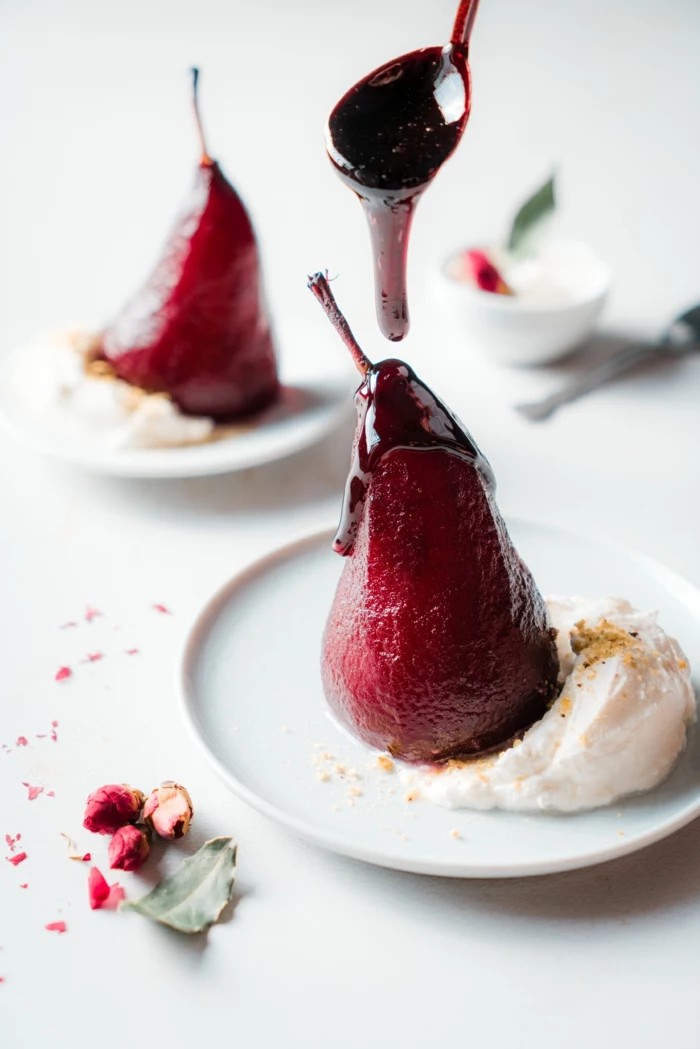 wine and sugar reduction drizzled, poached pears in red wine, served with cream on white plate