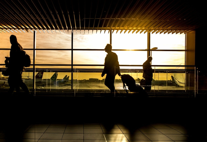 sun shining through airport windows, cheapest flights, people walking by with suitcases