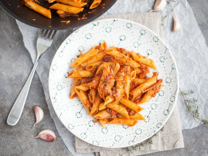 spicy penne, easy weeknight dinners, grated parmesan cheese on top, placed in white plate, fork on the side