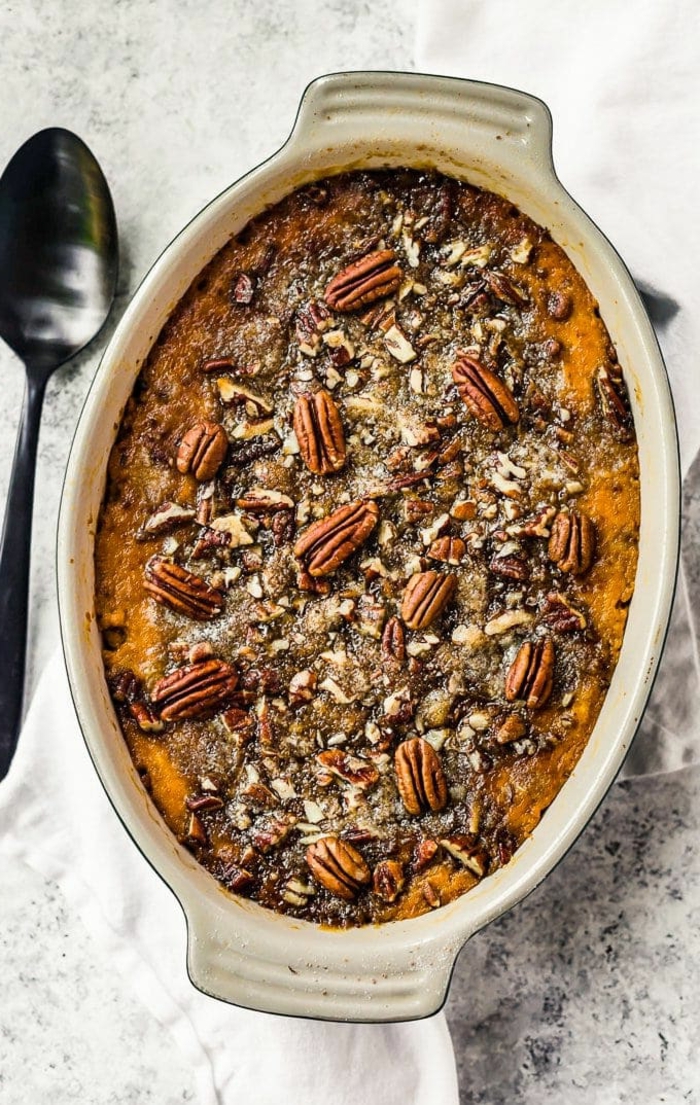 sweet potato casserole with pecans on top, baked in ceramic casserole dish, spoon on the side, easter dishes