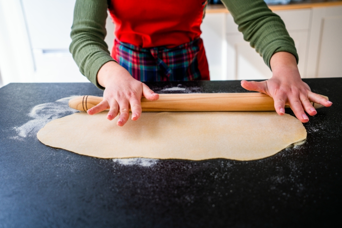 dough being rolled out, tagliatele recipe, black surface covered with flour