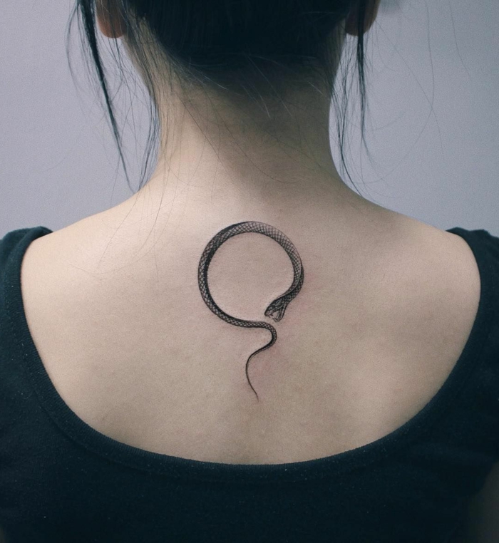 back tattoo, woman with black hair, wearing black top, snake eating its own tail