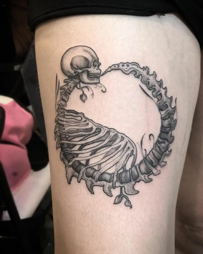 thigh tattoo of a skeleton, serpent eating its own tail, woman wearing black shorts