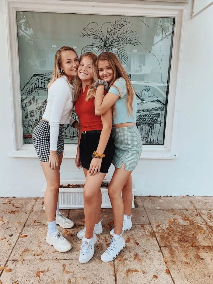 three girls posing for a photo, cute high school outfits, wearing skirts and crop tops, white sneakers