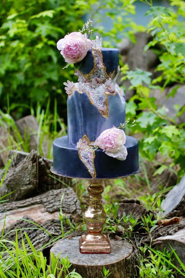 three tier cake, covered with blue marble fondant, decorated with purple rock candy and flowers, geode birthday cake