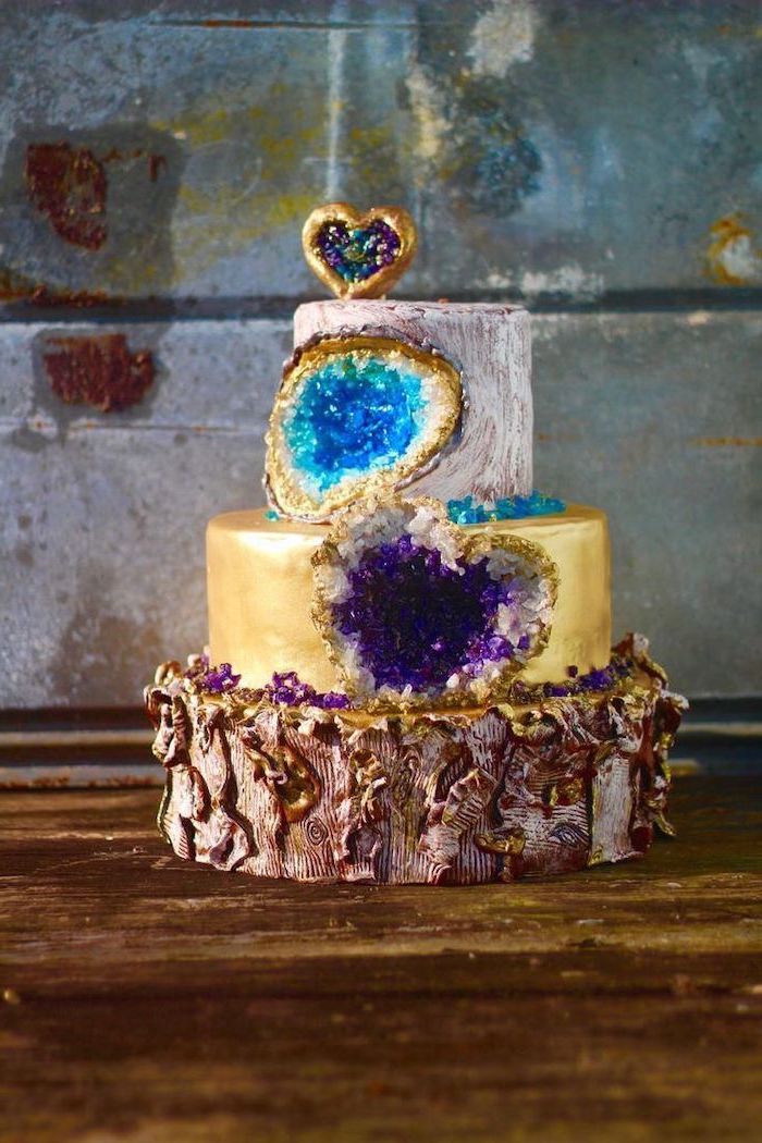 three tier cake, covered with white and gold fondant, decorated with turquoise and purple rock candy, pink geode cake