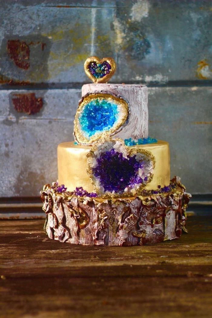 three tier cake, covered with white and gold fondant, decorated with turquoise and purple rock candy, pink geode cake