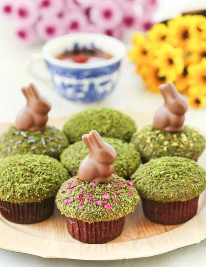 cupcakes with matcha powder on top, small chocolate bunnies cupcake toppers, easter dinner menu ideas, wooden plate