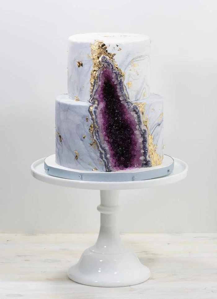 two tier cake, covered with white and grey marble fondant, pink geode cake, decorated with purple rock candy