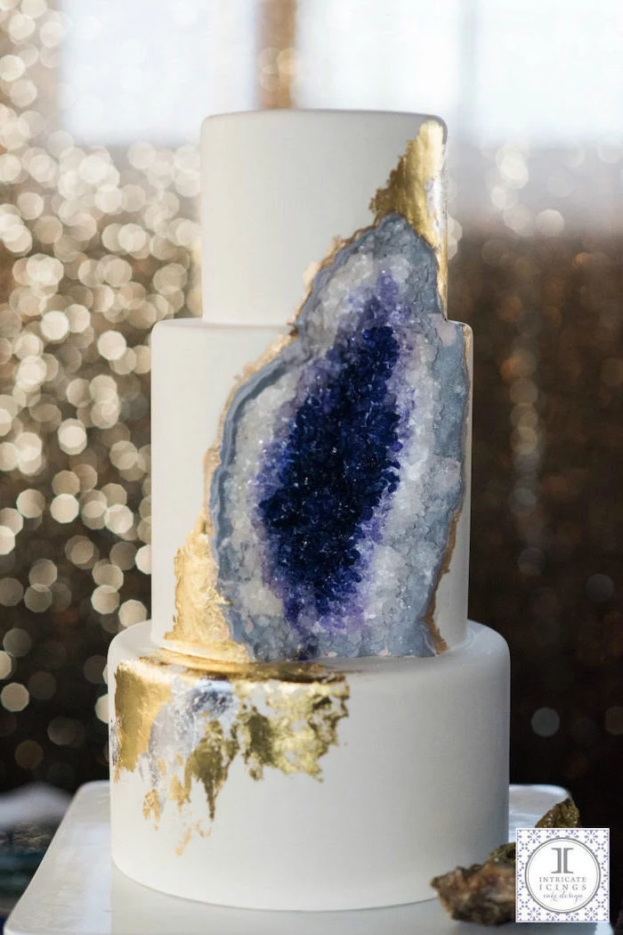 three tier cake, covered with white fondant, what is a geode cake, decorated with white and purple rock candy