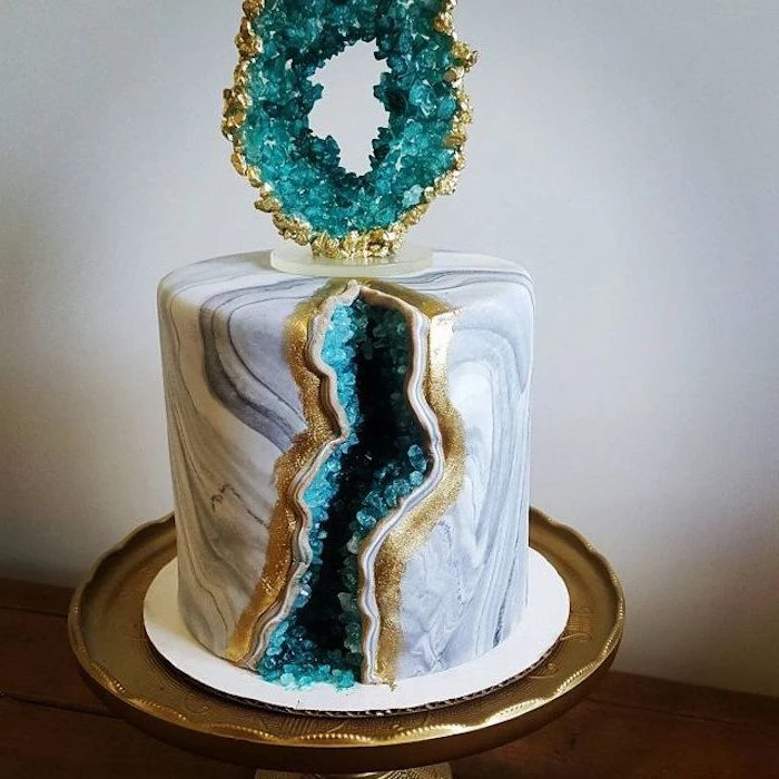 what is a geode cake, one tier cake, covered with white and grey marble fondant, decorated with turquoise rock candy