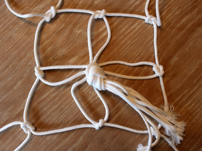 white macrame strands tied together, placed on wooden surface, diy hanging planter, step by step diy tutorial