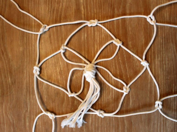 step by step diy tutorial, diy hanging planter, white strands of macrame tied together, placed on wooden surface