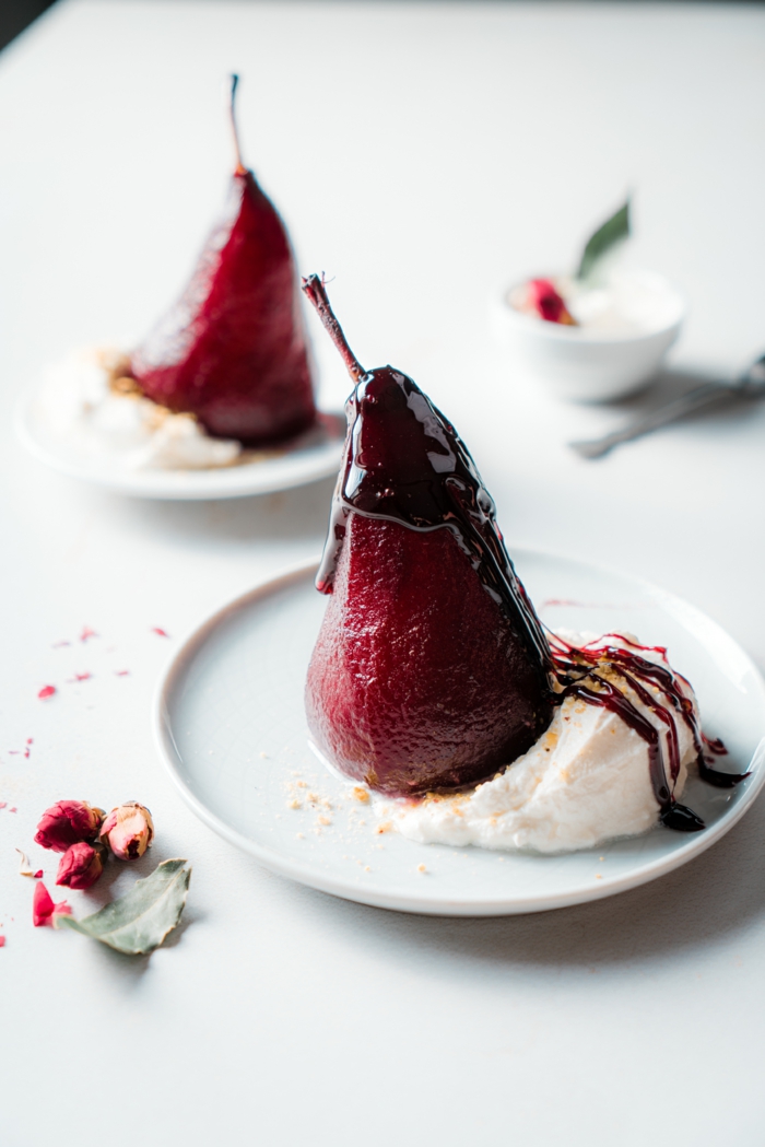 wine and sugar reduction drizzled, poached pears in red wine, served with cream, white countertop