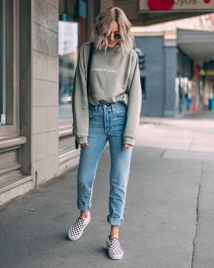 blonde woman walking on sidewalk, wearing jeans and grey sweatshirt, cute winter outfits for school, vans shoes