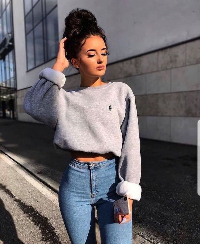 cute winter outfits for school, woman with black hair in a bun, wearing jeans and grey sweatshirt