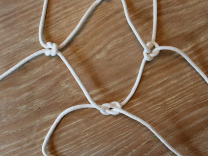 strands of macrame tied in three different placeds, diy hanging planter, placed on wooden surface