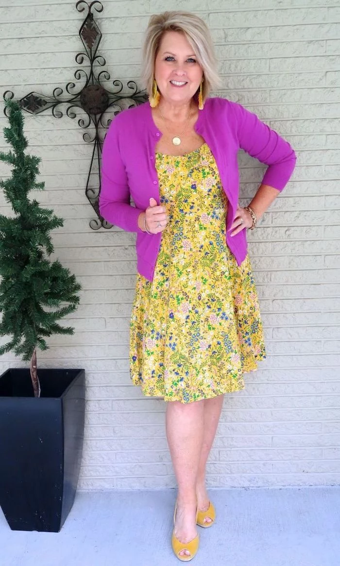 blonde woman wearing a yellow dress with floral print, yellow sandals, sunflower dress womens, pink cardigan