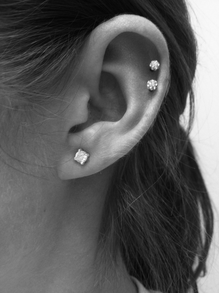 black and white photo, close up of an ear, multiple earrings with rhinestones, helix piercing