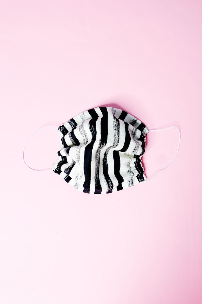 how to make your own surgical face mask, black and white striped face mask, placed on light pink surface