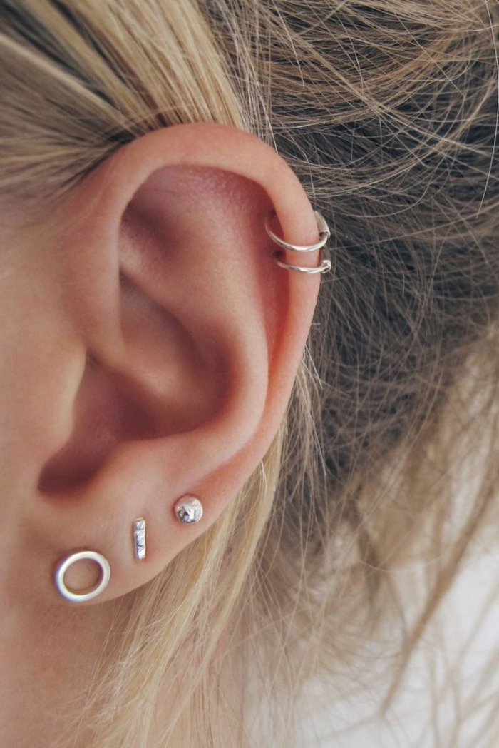double helix piercing, close up photo of an ear, multiple silver earrings, woman with blonde hair