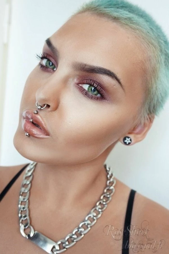 woman with pixie cut blue hair, green eyes, ashley piercing, septum ring piercing, nude lip gloss