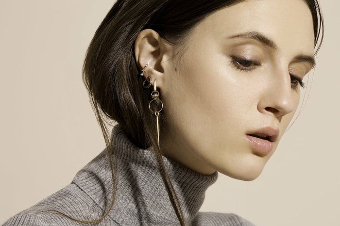 photo of brunette woman, wearing grey turtleneck blose, cartilage piercing, multiple earrings