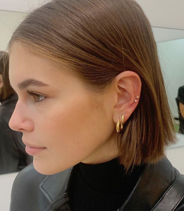 multiple golden earrings, woman with brown hair in short bob, cartilage ear piercings, black leather jacket