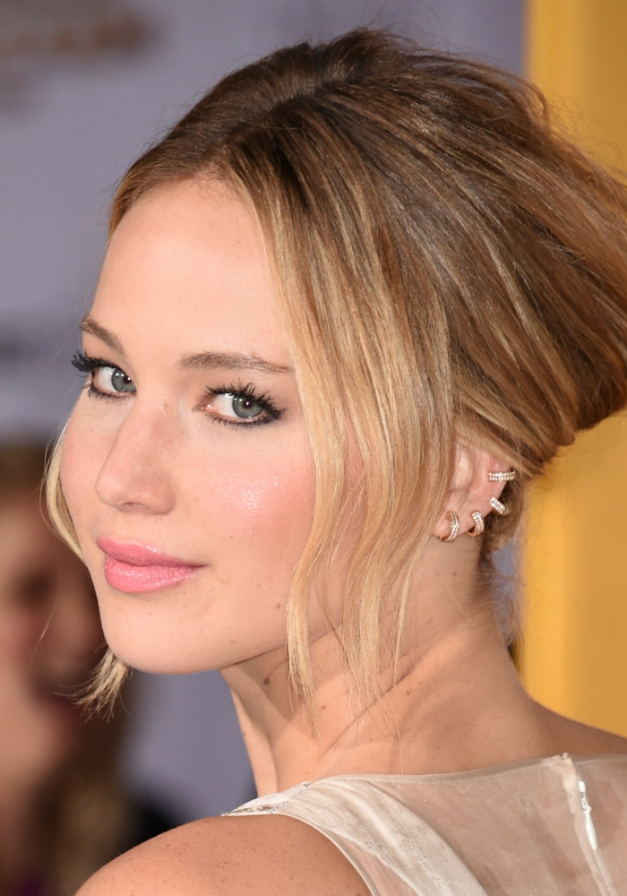 jennifer lawrence, blonde hair in a low updo, cartilage ear piercings, multiple ring earrings with rhinestones