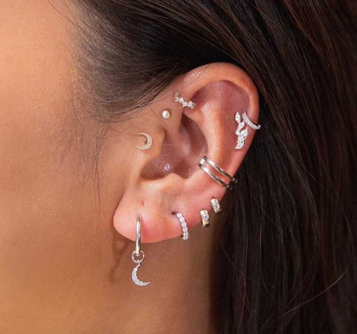 woman with brown hair, forward helix piercing, wearing multiple earrings with rhinestones, close up photo