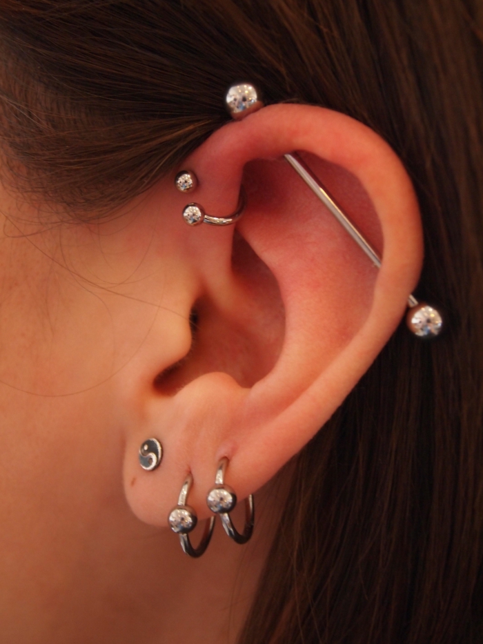 triple helix piercing, close up photo, woman with brown hair, multiple different silver earrings