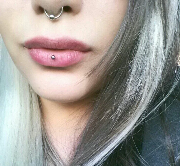 woman with ash blonde hair, lips with no lip gloss, middle lip piercing, septum ring piercing